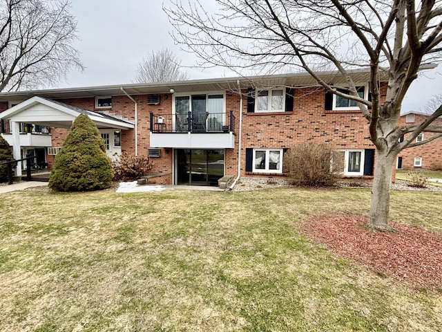 rear view of property with brick siding, a yard, and a balcony