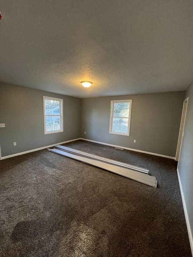 spare room featuring carpet, baseboards, and a textured ceiling