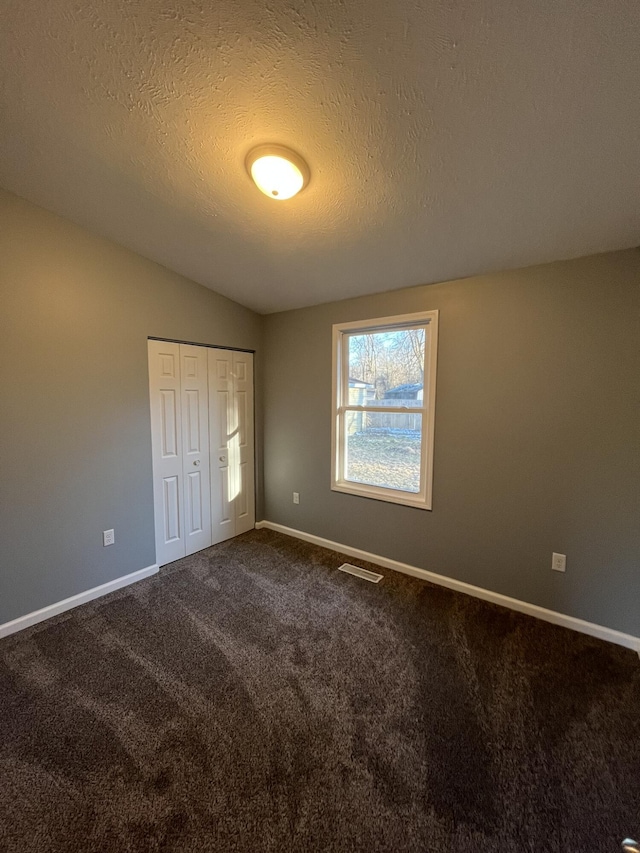 unfurnished bedroom featuring a closet, visible vents, dark carpet, and baseboards