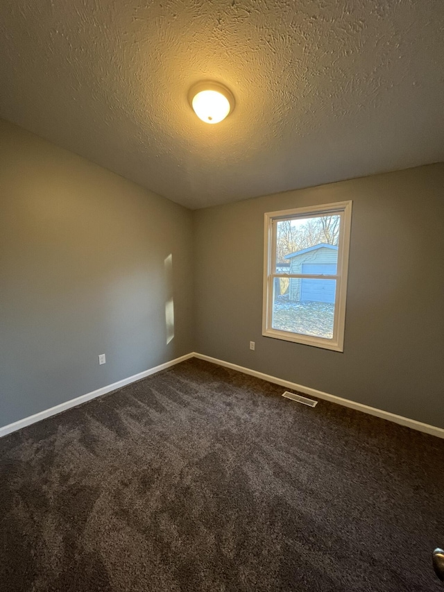 unfurnished room with baseboards, visible vents, and dark carpet