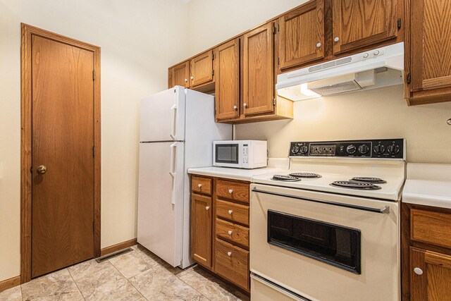 kitchen with white appliances, visible vents, brown cabinetry, light countertops, and under cabinet range hood