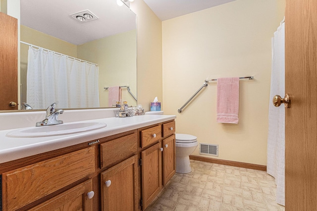 bathroom with toilet, vanity, visible vents, and baseboards