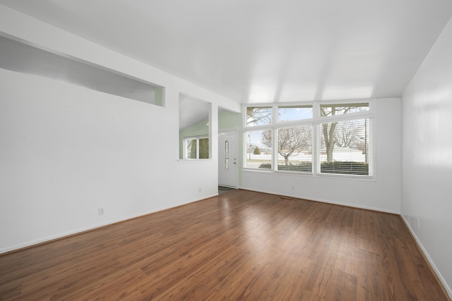 spare room with vaulted ceiling, dark wood-style floors, and baseboards