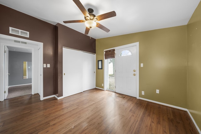 foyer featuring visible vents, baseboards, wood finished floors, and vaulted ceiling