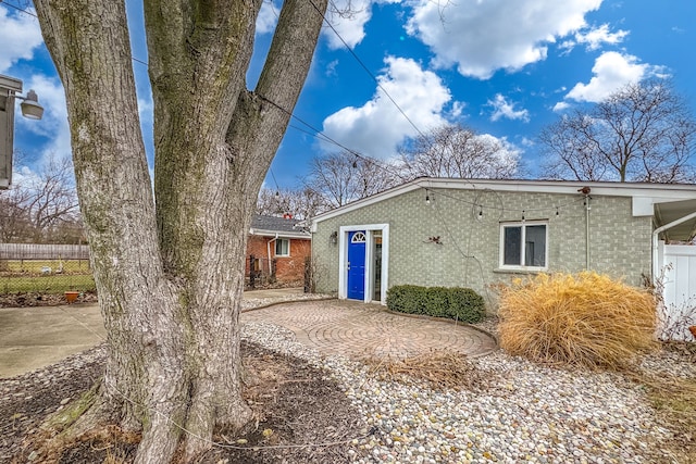 rear view of property featuring a patio area, fence, and brick siding