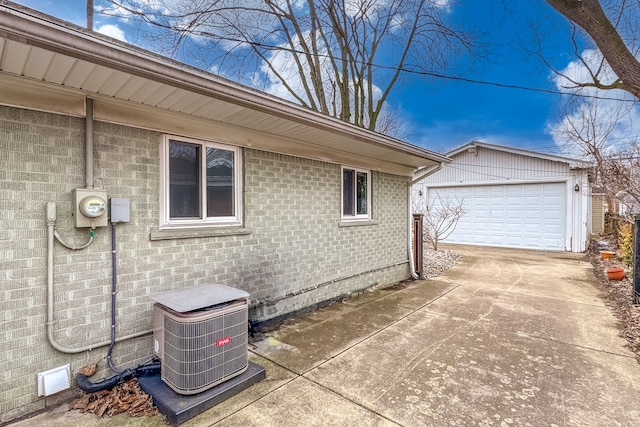 view of property exterior featuring central air condition unit, an outbuilding, a garage, and brick siding