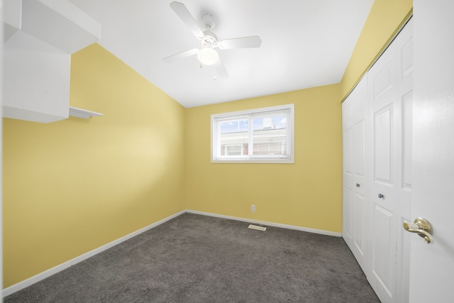 unfurnished bedroom with a closet, vaulted ceiling, baseboards, and dark colored carpet