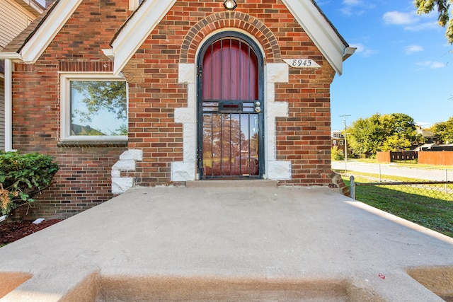 doorway to property with brick siding and fence