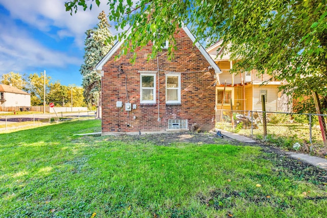 view of home's exterior with a yard, brick siding, and fence