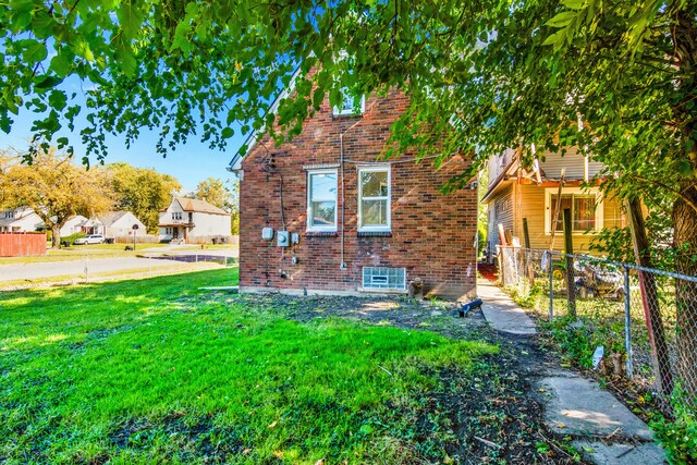 exterior space with a yard, fence, and brick siding