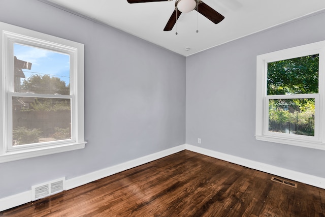 unfurnished room with dark wood-style floors, visible vents, ceiling fan, and baseboards