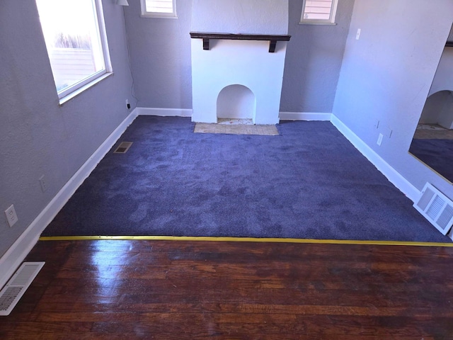 unfurnished living room featuring visible vents and baseboards