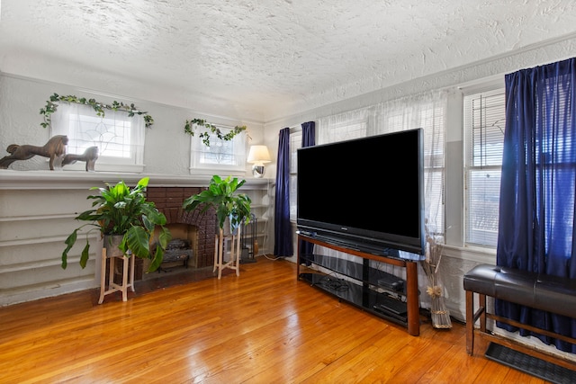 living area with a textured wall, a fireplace, wood-type flooring, and a textured ceiling