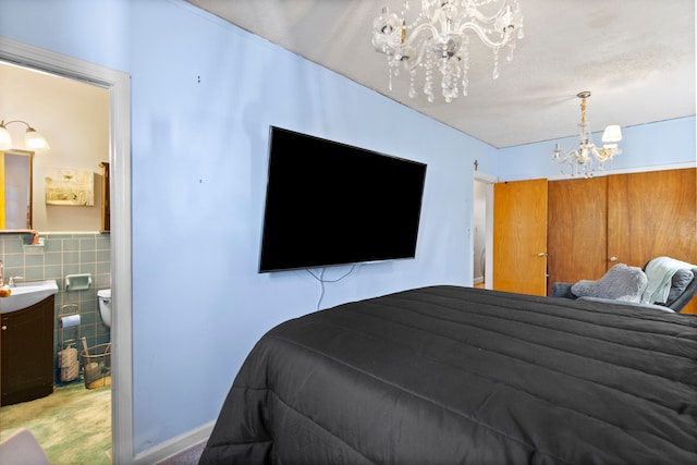 bedroom with a sink, connected bathroom, a notable chandelier, and tile walls