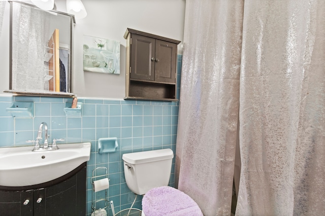 full bath with vanity, tile walls, toilet, and wainscoting