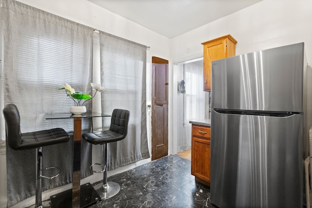 kitchen featuring brown cabinetry and freestanding refrigerator