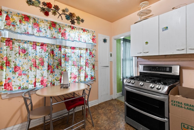 kitchen featuring white cabinets, baseboards, and range with two ovens