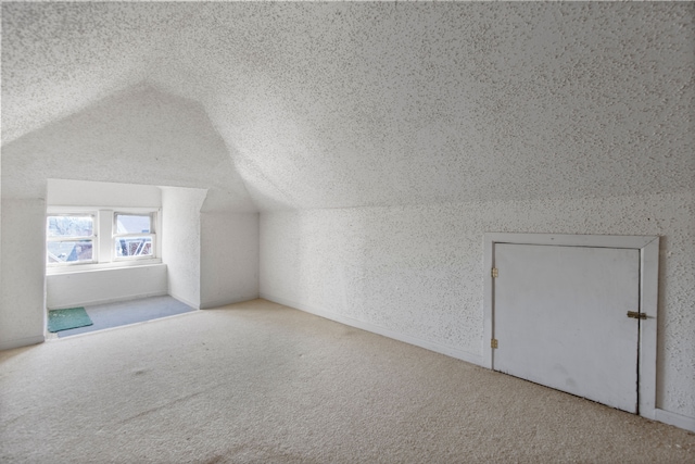 additional living space with a textured ceiling, lofted ceiling, and carpet floors