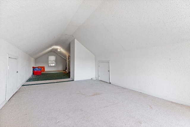 bonus room featuring vaulted ceiling, carpet flooring, baseboards, and a textured ceiling