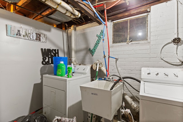washroom featuring laundry area, separate washer and dryer, and a sink