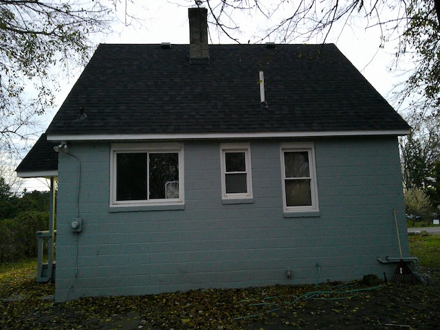 view of side of home with a shingled roof and a chimney