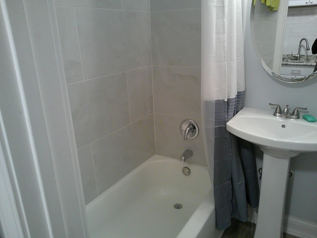 bathroom featuring a sink, backsplash, and shower / tub combo with curtain