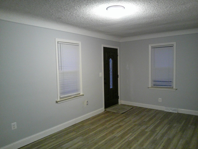 spare room with dark wood-type flooring, a textured ceiling, and baseboards