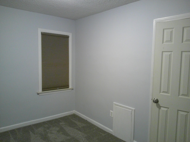 unfurnished room with dark carpet, a textured ceiling, and baseboards