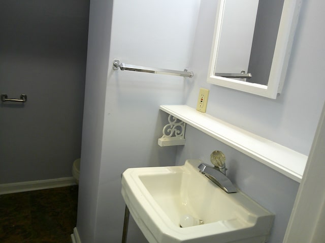 half bath with a sink, toilet, and baseboards