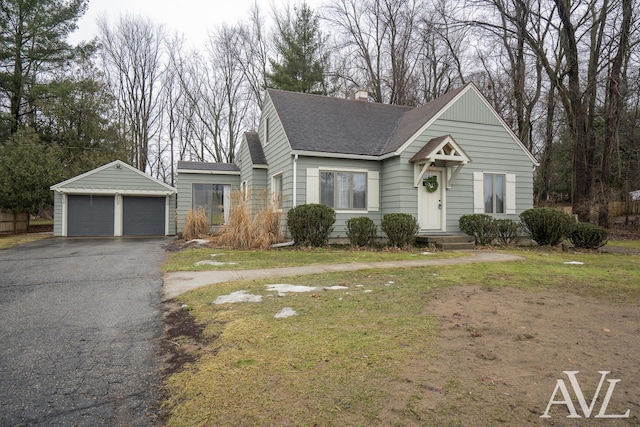 view of front of property with a shingled roof, a detached garage, a chimney, and an outbuilding