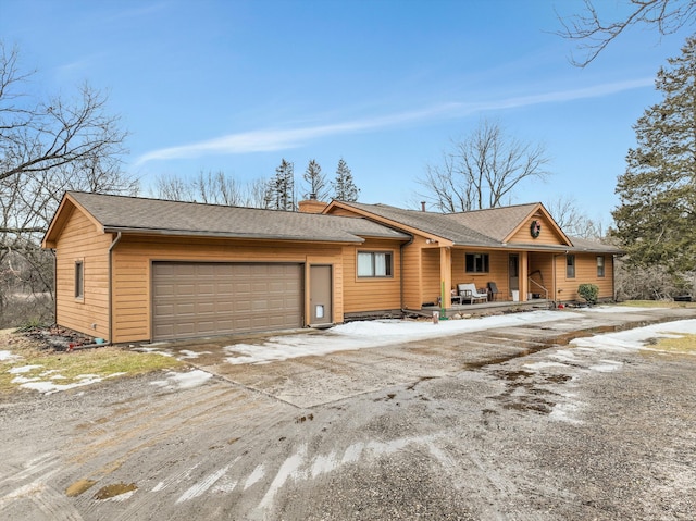 chalet / cabin featuring roof with shingles, driveway, and an attached garage