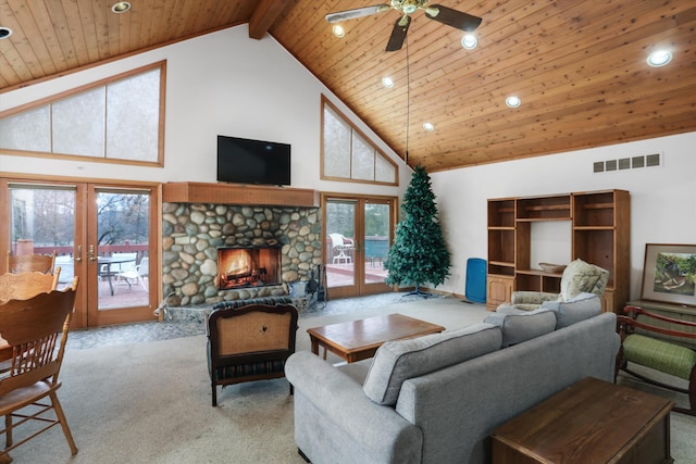 living area with carpet floors, french doors, visible vents, and a stone fireplace