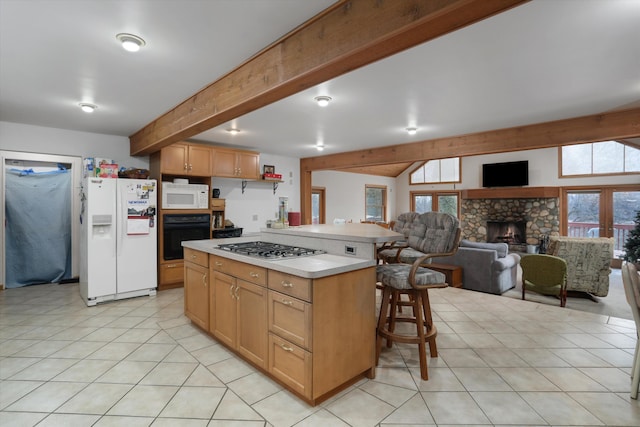 kitchen featuring white appliances, a breakfast bar, open floor plan, light countertops, and a fireplace