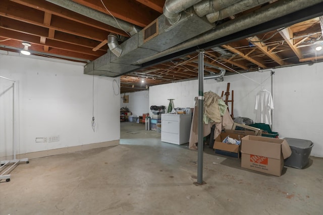 unfinished below grade area with concrete block wall, washer / dryer, and visible vents