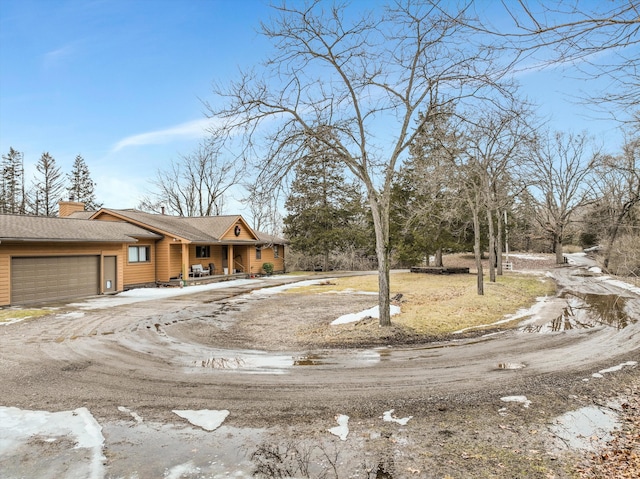 view of front of property featuring a garage, driveway, and a chimney