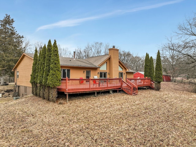 rear view of property with roof with shingles, a chimney, and a wooden deck