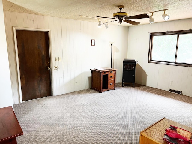 carpeted empty room featuring a ceiling fan, visible vents, and track lighting