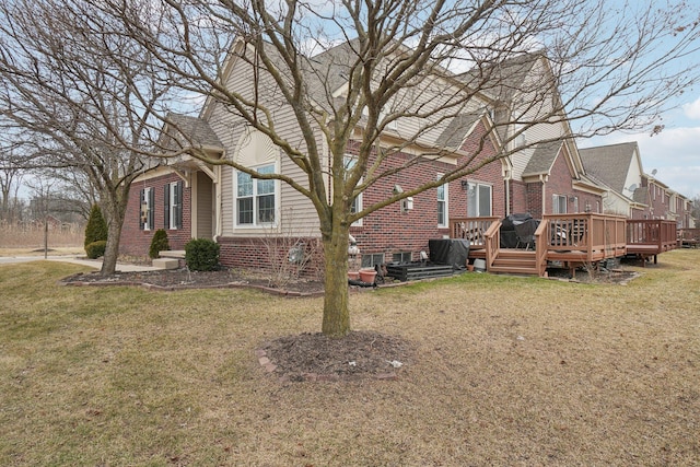 view of property exterior featuring a deck, brick siding, and a lawn