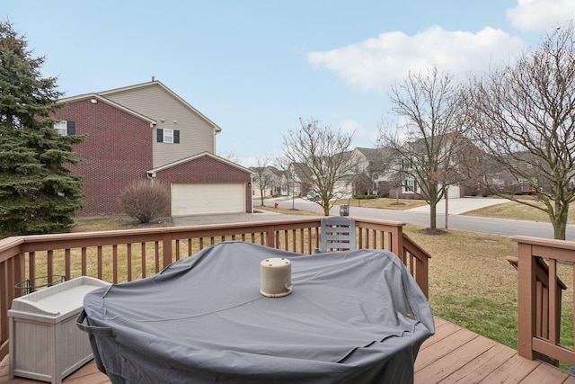 wooden deck with a garage and a grill