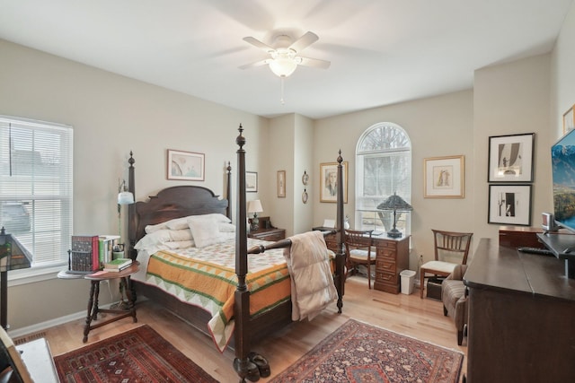 bedroom with multiple windows, light wood-type flooring, a ceiling fan, and baseboards