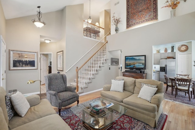 living area with baseboards, visible vents, stairway, and light wood finished floors