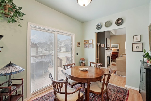 dining room with light wood-style floors, baseboards, and a glass covered fireplace