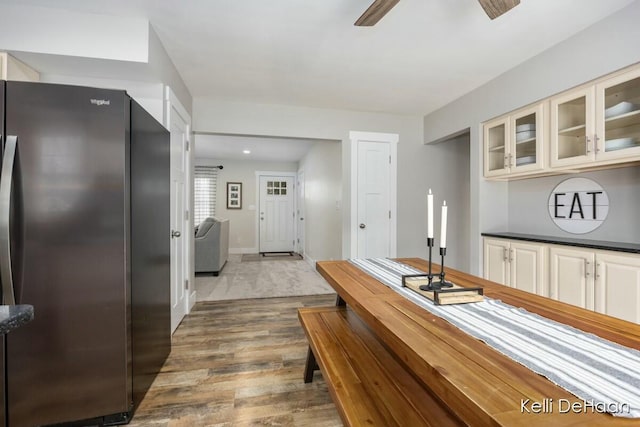 kitchen featuring baseboards, ceiling fan, glass insert cabinets, wood finished floors, and freestanding refrigerator