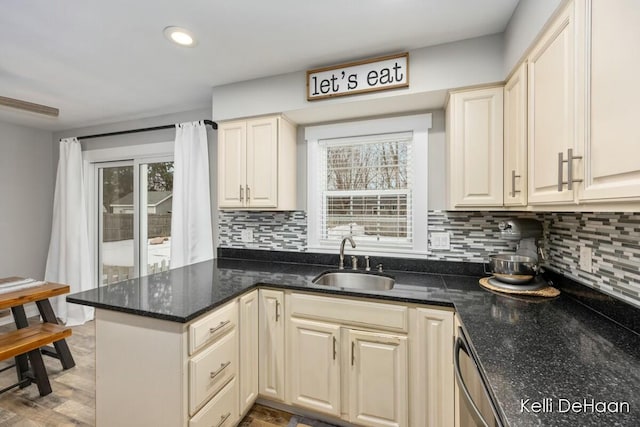 kitchen with recessed lighting, a peninsula, a sink, backsplash, and dark stone countertops