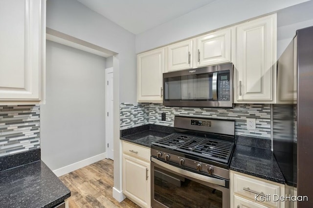 kitchen featuring light wood finished floors, dark stone counters, and stainless steel appliances