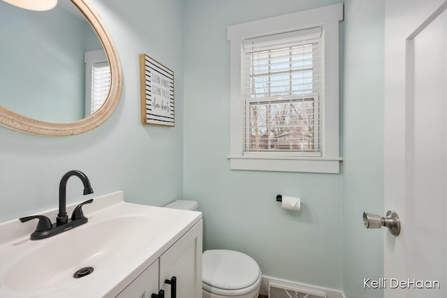 half bath with visible vents, vanity, and toilet