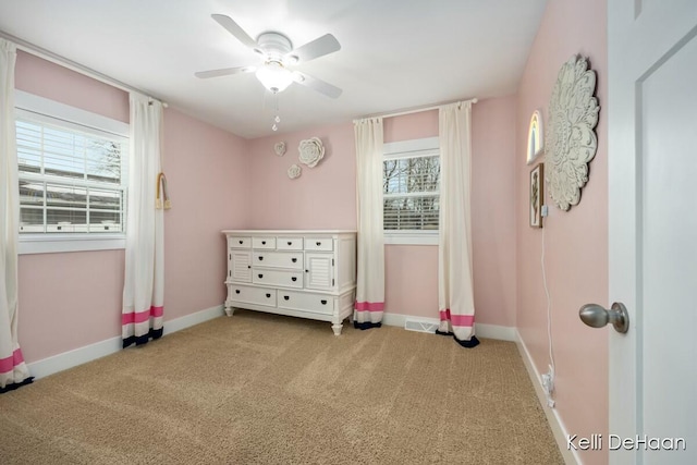 interior space featuring multiple windows, baseboards, and carpet flooring