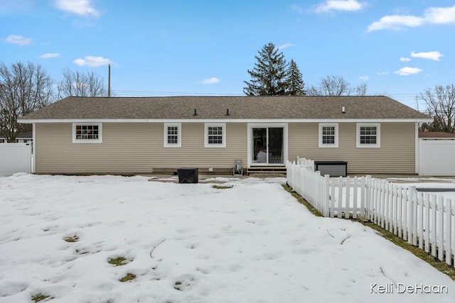 snow covered property featuring a garage and fence