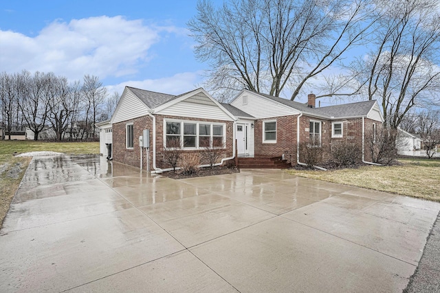 view of front of property with driveway, a chimney, a front lawn, and brick siding