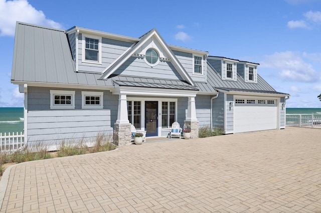 view of front of property featuring metal roof, a water view, fence, decorative driveway, and a standing seam roof